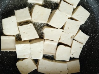 肉末烧豆腐,锅内倒入适量食用油，把切好的豆腐码平，煎至底部金黄色。