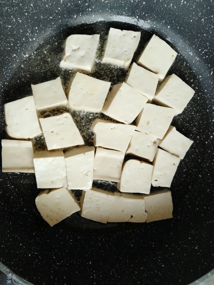 肉末烧豆腐,锅内倒入适量食用油，把切好的豆腐码平，煎至底部金黄色。