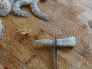 奥尔良日式凤尾虾,想要炸好的虾仁不卷曲，我们要把虾筋挑断，如图，用刀子横向在虾腹部切一排。