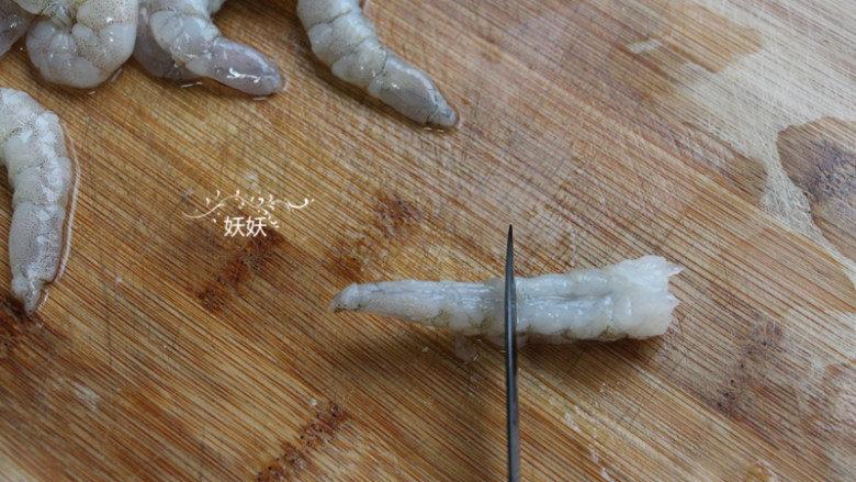 奥尔良日式凤尾虾,想要炸好的虾仁不卷曲，我们要把虾筋挑断，如图，用刀子横向在虾腹部切一排。