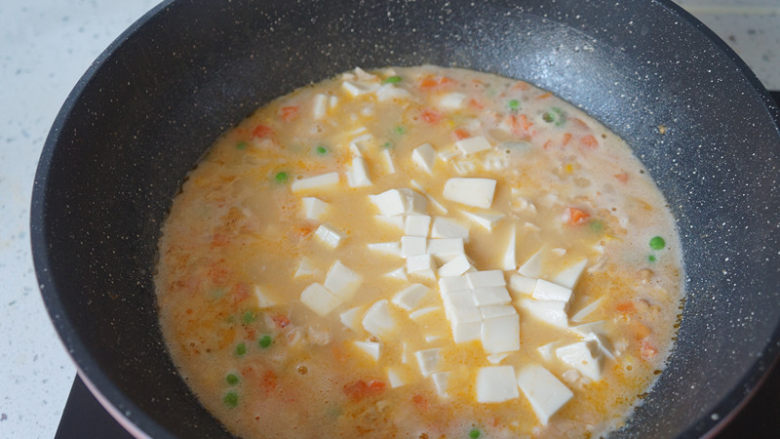 咸蛋虾仁豆腐煲,水开后倒入豆腐，小火煮三四分钟