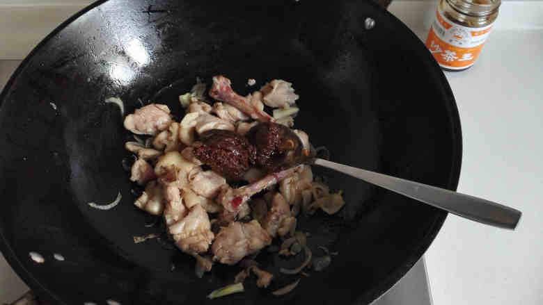鸡腿焖饭,炒至鸡腿肉收缩变色后，放入2大勺沙茶酱，炒匀
