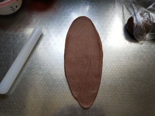 巧克力吐司,取一个面团擀成牛舌状。从上端卷起