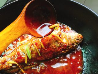 红烧春子鱼,利用勺子将调汁均匀的淋在鱼身上