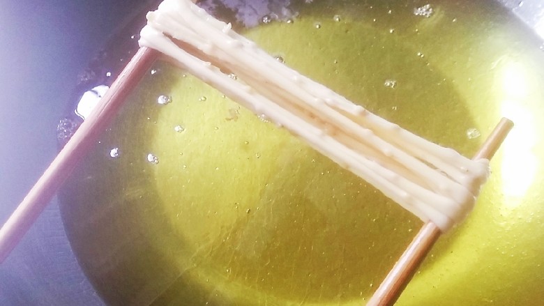 撒子,手指上的细条用两根筷子撑起来，再拉长一点，放入油锅