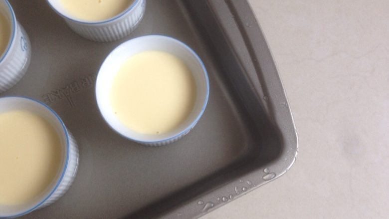 奶油布丁,烤盘里装有热水将布丁杯放入。