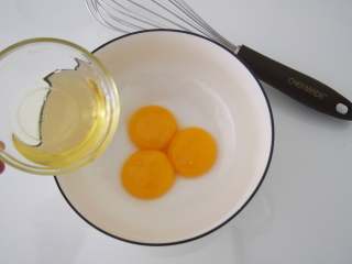 咖啡奶油卷,蛋黄和蛋清分离后，将蛋黄中加入玉米油，搅拌均匀。