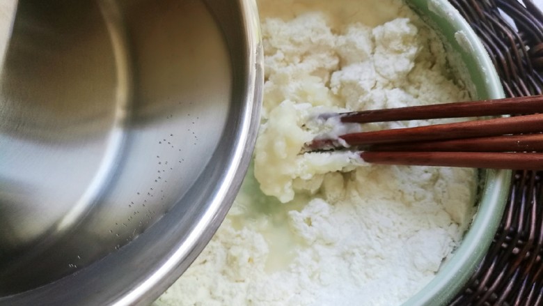 炸糖糕,沸水缓缓地倒入面粉里，边倒边用筷子顺时针搅拌。