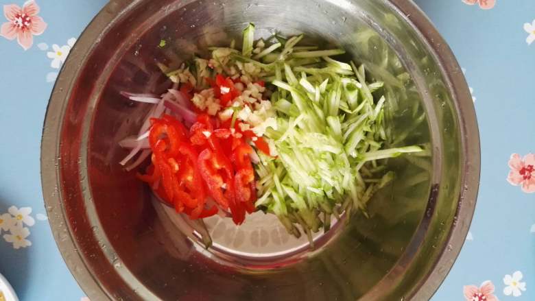 清凉解暑小拌菜,黄瓜、红椒、洋葱、蒜倒入搅拌盆中。

