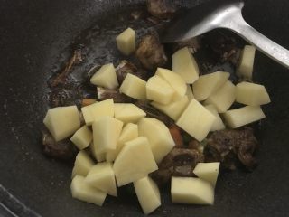新手菜谱，土豆排骨焖饭,把土豆，杂蔬倒入。翻炒均匀。