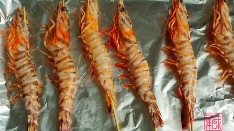 承味普罗旺斯迷迭香烤虾,先用对半切的蒜涂在烤纸上，虾用竹签串好后放在烤盘上