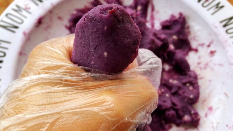 奶香坚果紫薯饼,戴上一次性手套，把奶粉和紫薯抓匀