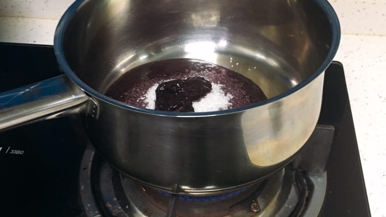 6寸蓝莓慕斯蛋糕,蓝莓泥放入煤气灶上加热，用刮刀翻拌，使细砂糖溶解于蓝莓泥中。