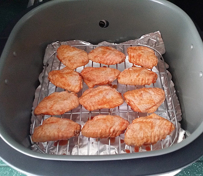 奥尔良烤鸡翅 ,将腌好的鸡翅正面朝上、放至空气炸锅的高架网上