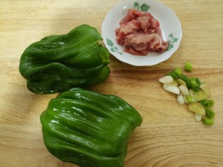 青椒炒肉,先准备两个青椒，一小块肉，还有葱姜蒜。把肉切成肉片。