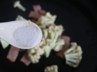 菜花炒培根,调入白糖、适量的盐，继续翻炒均匀。