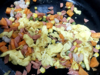 家常蛋包饭,锅中翻入切好的胡萝卜、火腿、虾仁丁，进行翻炒均匀。