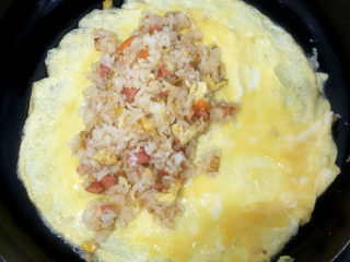 家常蛋包饭,倒入炒好的米饭，对合上蛋饼，用锅铲固定好封口。