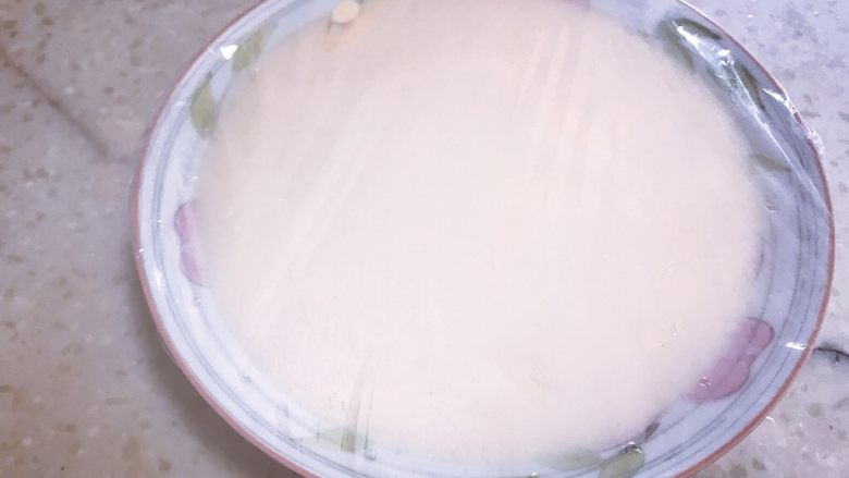 芒果双皮奶,倒入盘中，盖上一层保鲜膜，用牙签适当在膜上扎一些小孔，然后放入锅中蒸8分钟左右