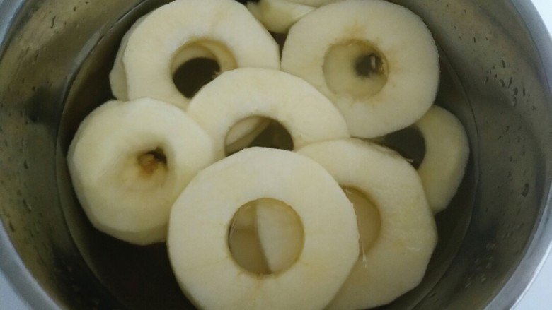 苹果新吃法，老少皆宜的苹果甜甜圈,碗里加入清水放少许盐进去再把苹果圈放进去浸泡以免氧化发黑。