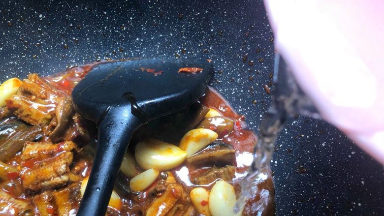 红烧鳝段,倒入50ml水，盖上盖子焖煮5分钟至汤汁浓稠