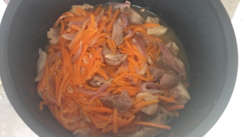 新疆手抓饭,将炒好的羊肉、胡萝卜洋葱放在米上，倒入适量热水，不要没过大米食材
