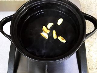 鸡翅焖锅,砂锅倒入适量的橄榄油，中火加热、放入蒜片，炒至金黄，有香味