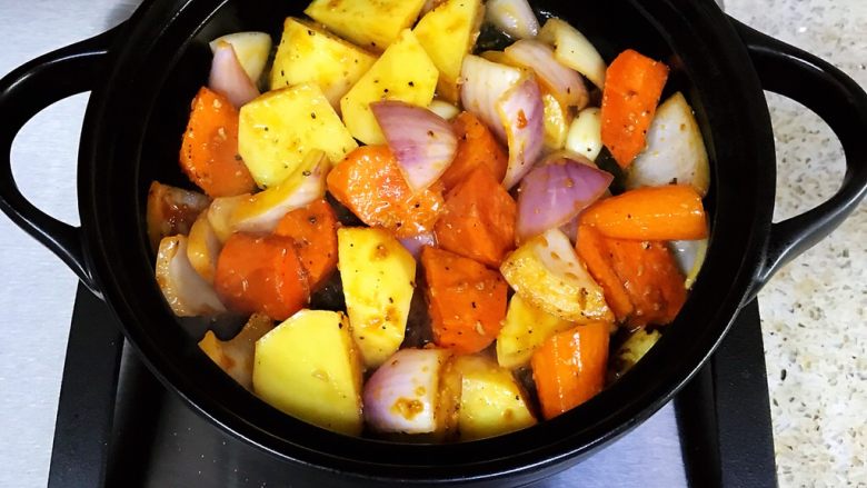 鸡翅焖锅,将拌好的土豆胡萝卜、洋葱块倒入砂锅，翻炒片刻