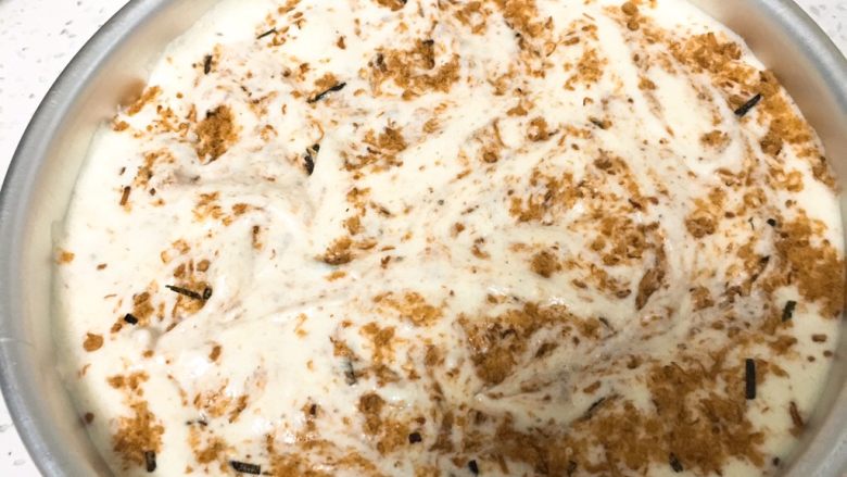 海苔芝麻肉松蛋糕,翻拌均匀的蛋糕糊倒入模具，震几下再加入另一半的海苔芝麻肉松，用竹签来回拉的方式拌匀。