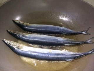 香煎秋刀鱼,6、放入秋刀鱼，小火慢煎。

让它们安静地待着，不要去动。

小贴士：注意看照片中，鱼旁边的一些花白的盐，这就是热油不能将盐全化开的状态。虽然看着盐多，其实热油的含盐量处于饱和状态，此时鱼主要通过油来吸收盐的味道，每次靠着这点就必定煎出咸淡适宜的香煎鱼。