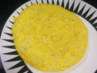 快手营养早餐：芝士甜玉米鸡蛋饼,然后将鸡蛋饼倒扣到碟子上。