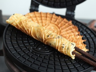 黑芝麻蛋卷,立即趁热用筷子将蛋卷卷起，凉了就变硬卷不起来了