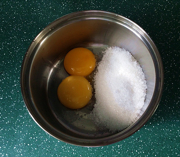 双色香草大冰砖,蛋黄、白糖倒入奶锅中搅拌至完全融化