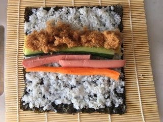 寿司,中间放入黄瓜条、胡萝卜条、鸡蛋皮、火腿肠，适量肉松