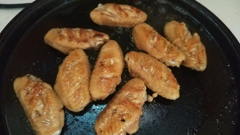 可乐鸡翅,锅内放少许油，将腌至好的鸡翅放入锅内，煎至金黄取出