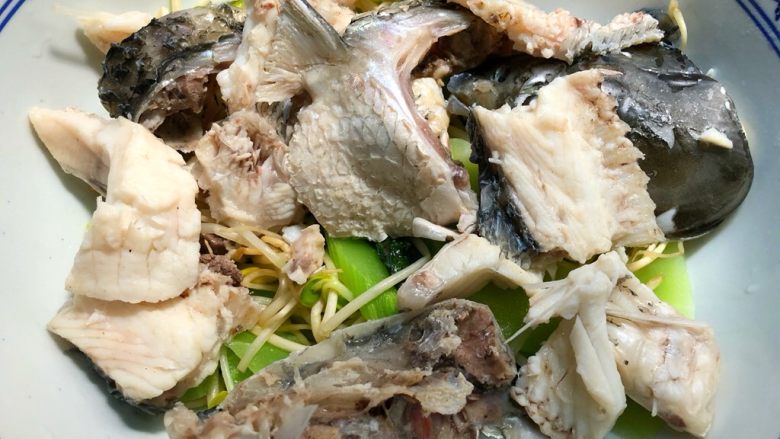 沸腾鱼,鱼头鱼骨焯熟用漏勺捞到青菜上