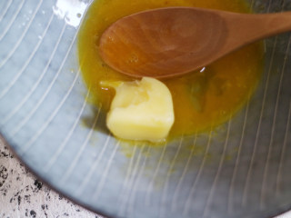 营养丰富的健康早餐之鸡蛋松饼,把鸡蛋打在碗里，将黄油放入装鸡蛋的碗中，将黄油充分融化在鸡蛋中。
