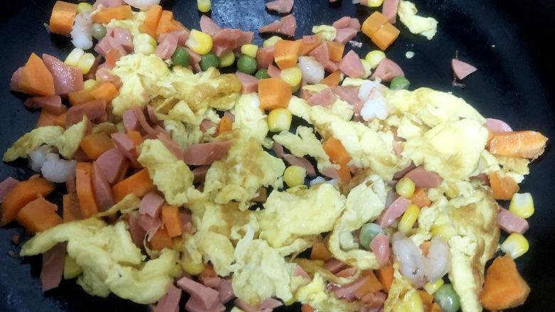 家常蛋包饭,锅中翻入切好的胡萝卜、火腿、虾仁丁，进行翻炒均匀。