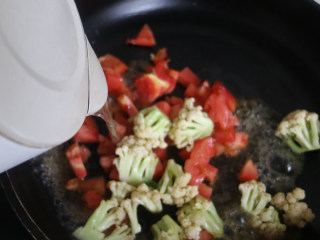 番茄炒菜花,锅中倒入适量的开水，大火煮开5分钟后食物全熟即可盛盘。