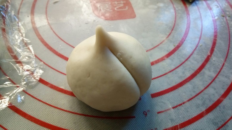 寿桃豆沙包,用手掌在顶端捏出小尖，拿刀背压出痕迹，稍微压深点，因为还要进行二次发酵。依次做好……