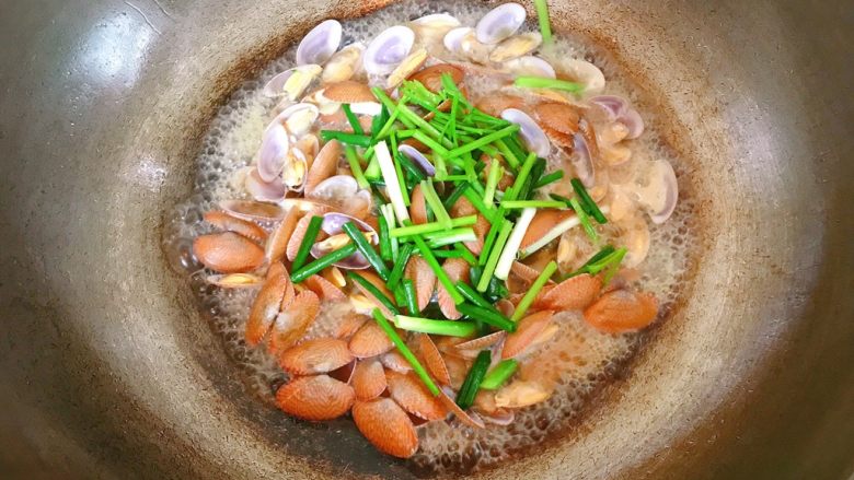 炒花蛤,炒至花蛤全部开口，放入葱和芹菜。炒匀。