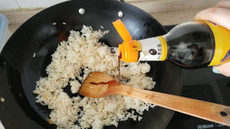 快手早餐 酱油蛋炒饭,第4步，锅里还有油，直接倒入米饭，用铲子将米粒捣碎成一粒一粒的。加入生抽，炒拌均匀。如果家里油老抽，推荐老抽，色泽更好看！