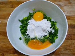 快手早餐葱花鸡蛋饼,小葱切葱花，放入碗中，倒入面粉，打入鸡蛋。
