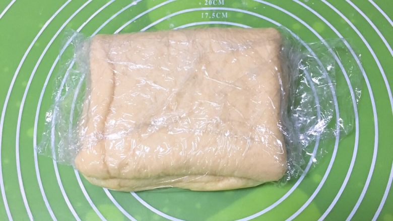 奶香牛角包,保鲜膜包裹起来，放入冰箱冷冻30分钟。