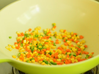 蔬菜米饭饼,锅里放少量油，依次放入胡萝卜、玉米、青椒，炒至断生后盛出放凉待用