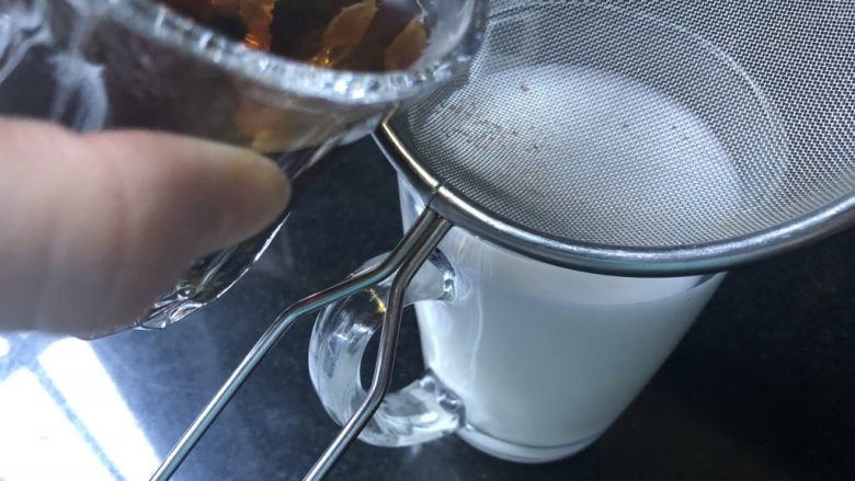 蜜桃乌龙奶茶,慢慢的将乌龙茶沿牛奶杯的边缘往下倒。注意茶汤现在还是比较热的，小心烫手。