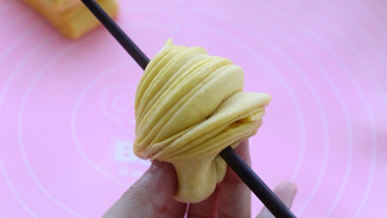南瓜泥花卷,然后绕到筷子上，把接头部位捏到一起，另一只手将筷子转动一圈