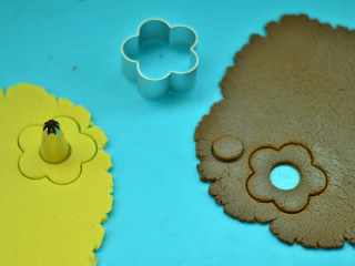 双色花朵饼干,用磨具压出花朵的样子，再用裱花用具压出圆心 