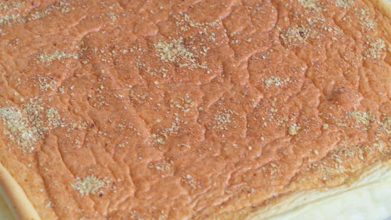小麦胚芽蛋糕卷,放入烤箱中，170度烘烤18分钟。出炉后晾至不烫手，把油纸四周撕开。