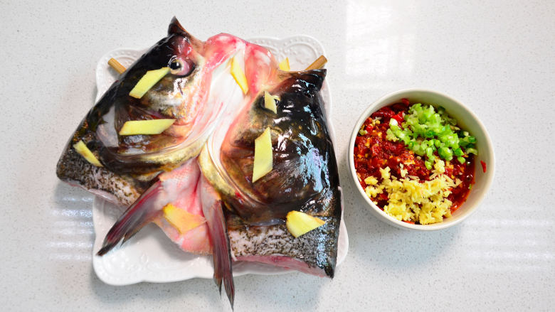 鲜美剁椒鱼头,沥干水的鱼头架在碟子上，在鱼头上摆上几片姜，可以随自己喜好。淋上一些料酒